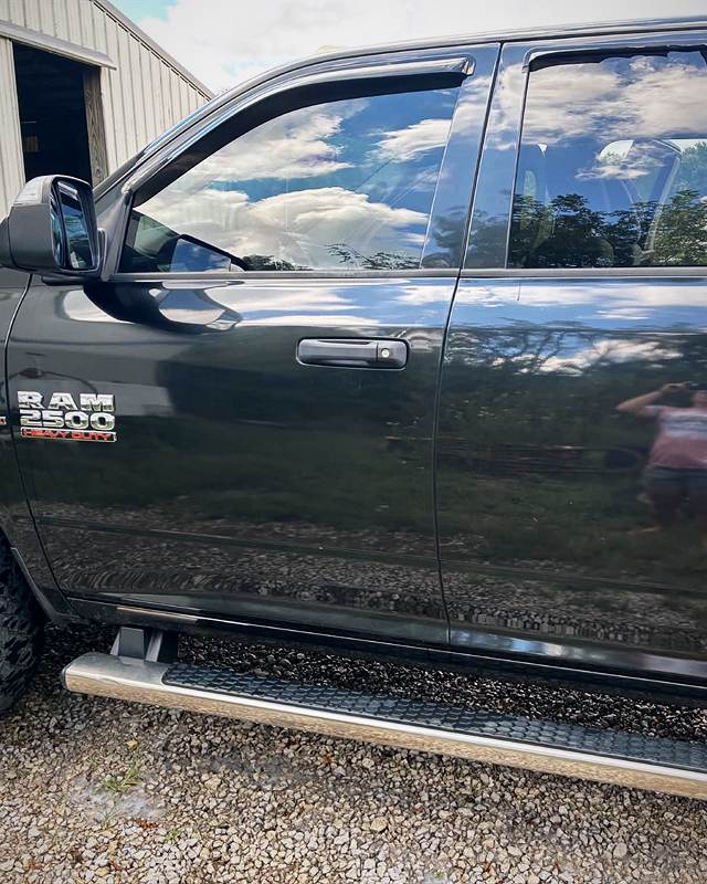 Side of a black Ram crew cab with deep reflections in the doors